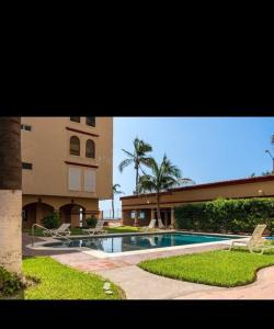a swimming pool with two chairs and a building at Comfortable apartment, right on the seafront in Mazatlán +18 photos