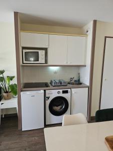 a kitchen with a washing machine and a microwave at Le cosy des Sables Blancs in Douarnenez +13 photos