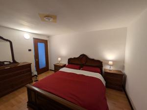 a bedroom with a red bed with two dressers and a mirror at Il Nido sul Torrente in Coazze
