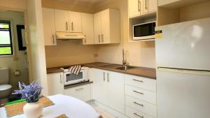 a kitchen with white cabinets and a vase of flowers on a table at The Denman Lodge in Brisbane