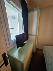a room with a computer monitor on a desk with a window at Le cosy des Sables Blancs in Douarnenez