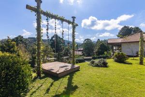 a garden with a wooden swing in a yard at Refúgio de Montanha em Monte Verde para Famílias e Amigos com 4 Suítes in Monte Verde