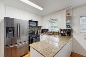 a kitchen with white cabinets and a stainless steel refrigerator at The Lazy Oak Retreat in Rockport