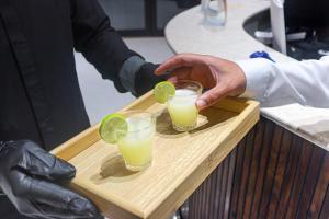 a person holding two glasses with lime slices on a tray at فندق تربل ثري in Medina