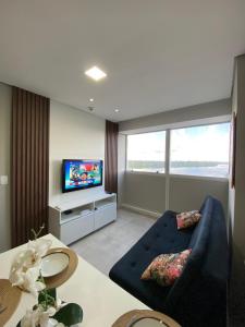 a living room with a blue couch and a tv at Flat aconchegante em Recife in Recife