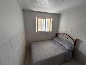 a small bed in a room with a window at Xangri-lá Beach House in Xangri-lá +2 photos