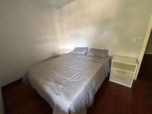 a small bedroom with a white bed and a night stand at Xangri-lá Beach House in Xangri-lá