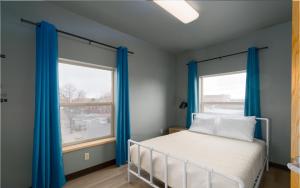 a bedroom with blue curtains and a bed and a window at Brewster Hall in Cheney