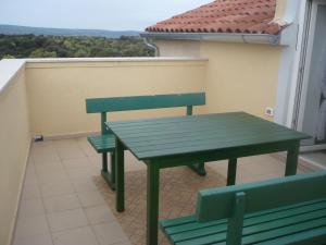 a green table and two benches on a balcony at House Dragica in Cres +18 photos