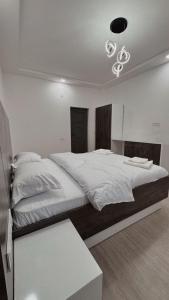 a bedroom with a large white bed with a chandelier at Prime House in Akunkʼ +6 photos