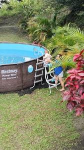 two people standing next to a swimming pool at Mi Cabaña in Nimaima