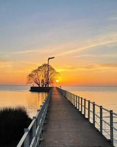 a pier leading to the ocean with a sunset at Olivos Stay in Olivos