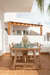 a wooden table with chairs and a vase on it at Siete Villas Olivencia Natural in Agua Amarga