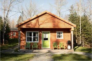 a small cabin with green chairs and a door at Lawrencetown Lodge - The Pine 2 Bed Room in Three Fathom Harbour