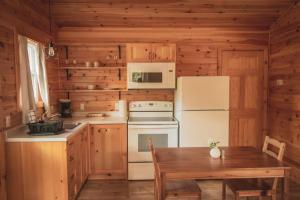 a kitchen with a stove and a refrigerator and a table at Lawrencetown Lodge - The Pine 2 Bed Room in Three Fathom Harbour