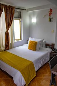 a bedroom with a large bed with a yellow blanket on it at Hotel Royal Suite in Manizales +49 photos
