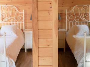 two beds in a room with wooden walls at Lawrencetown Lodge - The Pine 2 Bed Room in Three Fathom Harbour +7 photos