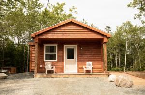a small log cabin with two chairs and a door at Lawrencetown Lodge - The Pine 2 Bed Room in Three Fathom Harbour