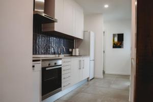 a kitchen with white cabinets and a black stove top oven at Artist’s corner in central Caldas in Caldas da Rainha
