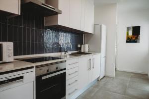 a kitchen with white cabinets and a black refrigerator at Artist’s corner in central Caldas in Caldas da Rainha +24 photos