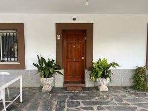 a wooden door in a white building with two potted plants at Casa familiar La Cabra in Talavera de la Reina