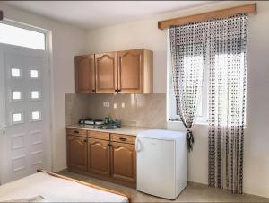 a kitchen with wooden cabinets and a white refrigerator at Apartments In Amor in Ulcinj