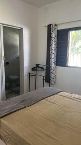 a bedroom with a bed and a window and a bathroom at Pousada Rensule in Bertioga