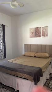 a bed in a bedroom with three pictures on the wall at Pousada Rensule in Bertioga