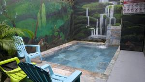 a swimming pool with two chairs and a mural at Red Frog Rooms in Fortuna