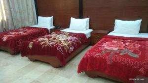 two beds in a room with red and white sheets at Sunrise BnB in Karachi
