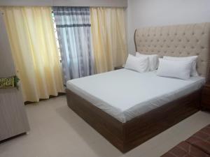 a bedroom with a large bed with white pillows at Sunrise BnB in Karachi