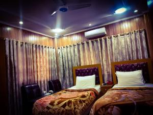 two beds in a room with curtains and curtainsktop at Sunrise BnB in Karachi
