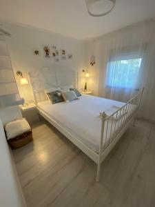 a bedroom with a white bed with a white bed frame at Vikendica Fruška lipa in Čortanovci