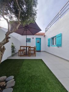 a patio with a table and an umbrella at Alba Odeceixe - casa aurea in Odeceixe