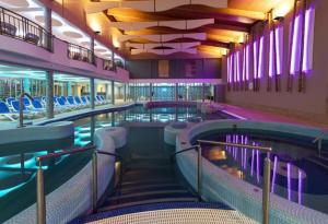 a swimming pool in a building with purple lighting at Karos Kristály Apartman in Zalakaros