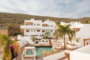 a large white house with a swimming pool and palm trees at Siete Villas Olivencia Natural in Agua Amarga