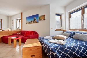 a bedroom with a bed and a red couch at Dolomiti Comfortspace Free Parking in San Niccolò Comèlico