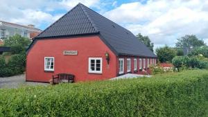 a red barn with a black roof at Stouwhuset Øster Hurup in Hadsund