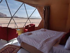 a bed and two chairs in a room with a window at Star Gate Camp in Wadi Rum