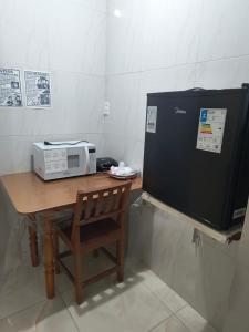 a microwave sitting on a wooden table with a chair at Flat Padim Ciço in Piranhas