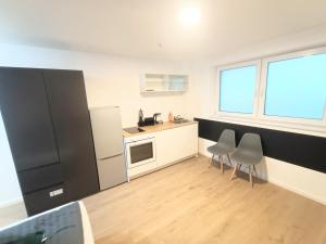 a kitchen with a black refrigerator and two chairs at Deluxe Studio-Apartments in Mörfelden-Walldorf