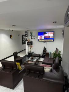a living room with couches and a flat screen tv at Hotel Royal Suite in Manizales