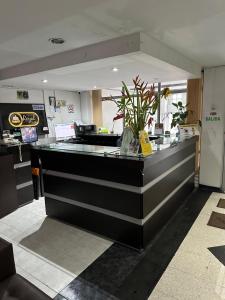 a lobby with a counter with a vase of flowers at Hotel Royal Suite in Manizales