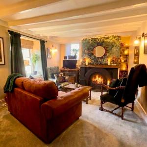 a living room with a couch and a fireplace at Thatched Cottage on Northumberland border in Kirk Yetholm