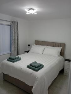 a bedroom with a white bed with green towels on it at the foyle bridge apartment in Derry Londonderry