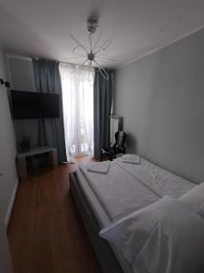 a bedroom with a large white bed and a television at Na Sadowej in Grodzisk Mazowiecki