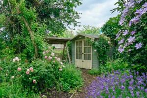 a garden with flowers and a small shed at Thatched Cottage on Northumberland border in Kirk Yetholm