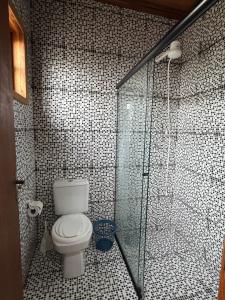 a bathroom with a toilet and a glass shower at Chalé aconchegante em Resende in Resende