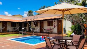 a patio with a table and an umbrella and a pool at Vila Bonita Guest House in Alto Paraíso de Goiás