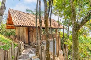 a wooden house with a fence and trees at Pousada Parador 33 in Biguaçu